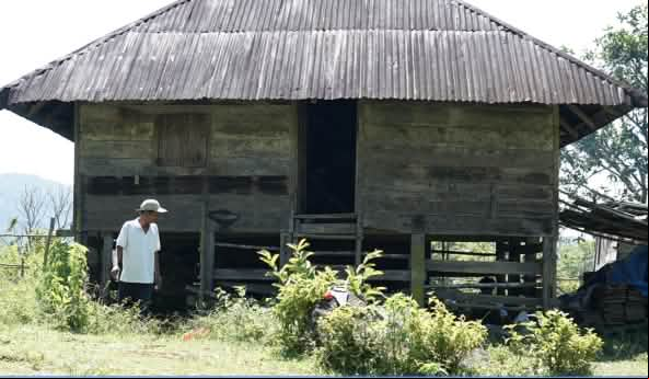 Una persona delante de una antigua casa de madera