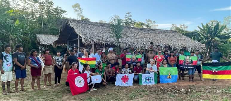 Grupo de personas en el territorio indígena Ka'apor posa con banderas